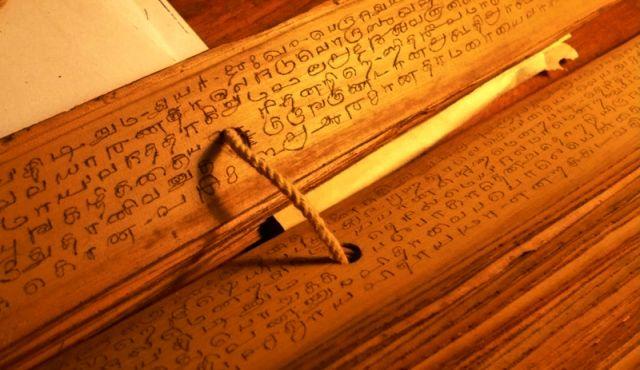 Ancient vedic manuscript with sacred texts and traditional writing instrument